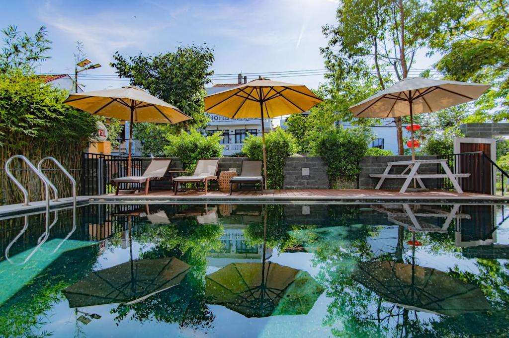 una piscina con sombrillas, mesas y sillas en Hoi An Majestic Villa, en Hoi An