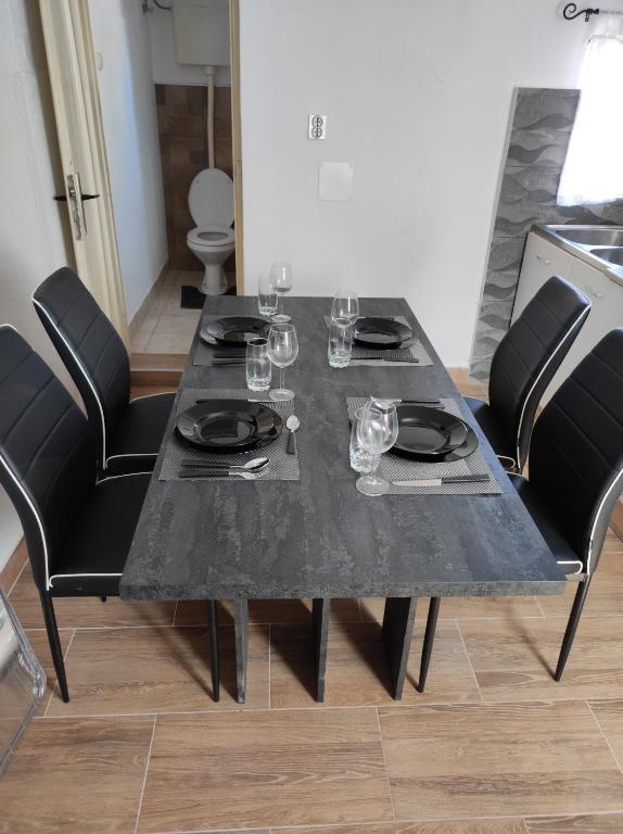a black dining table with black chairs and wine glasses at Apartman Selce in Selce