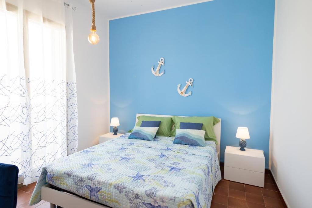 ein blaues Schlafzimmer mit einem Bett und zwei Lampen in der Unterkunft Tre Fontane - The House of The Sailor near the Beach in Tre Fontane