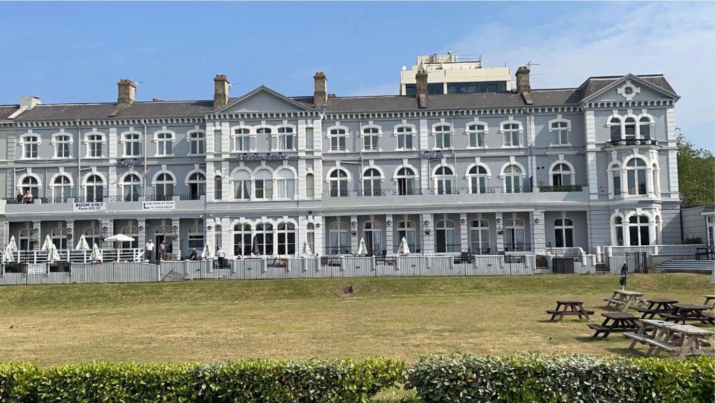 ein großes weißes Gebäude mit Tischen davor in der Unterkunft Royal Grosvenor Hotel in Weston-super-Mare