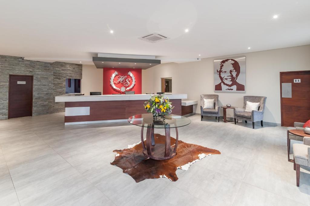 vestíbulo con sala de espera con mesa y sillas en Hotel Savoy and Conference Centre, en Mthatha