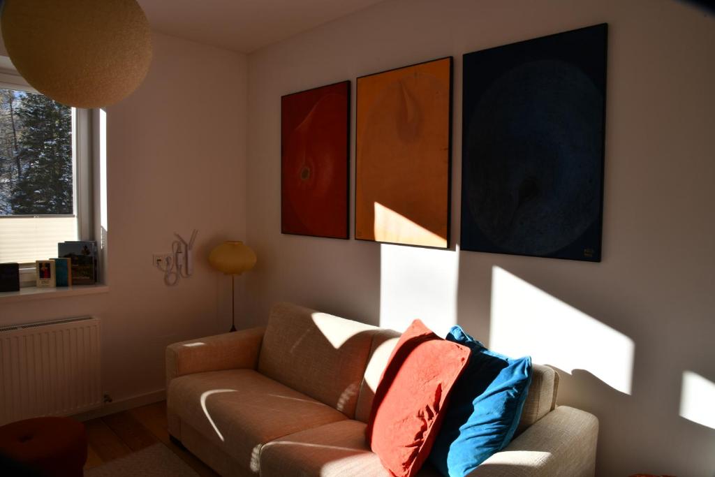 a living room with a couch and paintings on the wall at Serpentin Apartment in Turracher Hohe