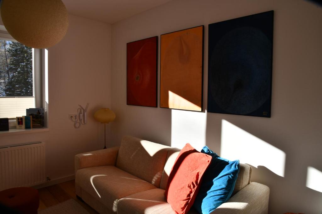 a living room with a couch and paintings on the wall at Edelstein Apartments in Turracher Hohe