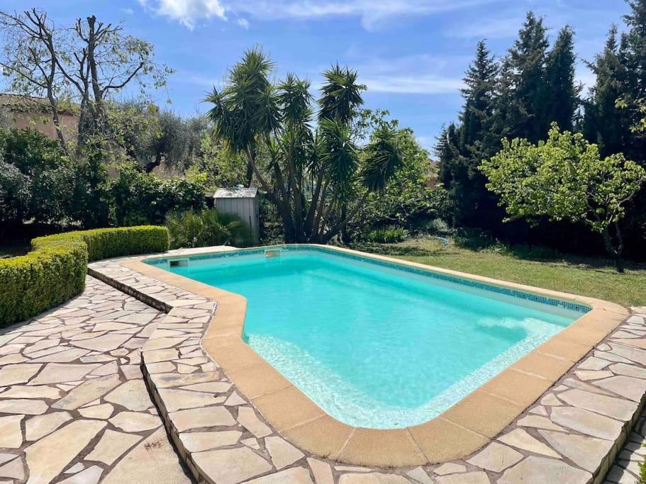 einen Pool im Garten mit einer Steinterrasse und Bäumen in der Unterkunft Villa provençale avec piscine et jardin au calme in Opio