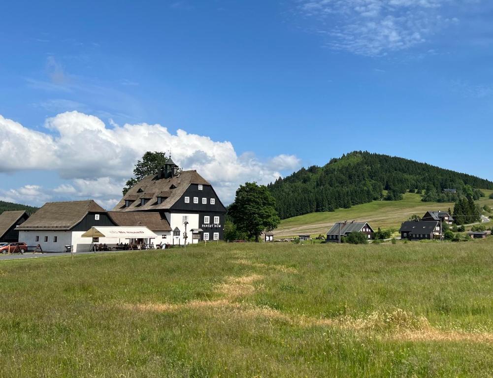 ein Bauernhof mit einem großen Grasland und Gebäuden in der Unterkunft Panský dům - Jizerka in Jizerka