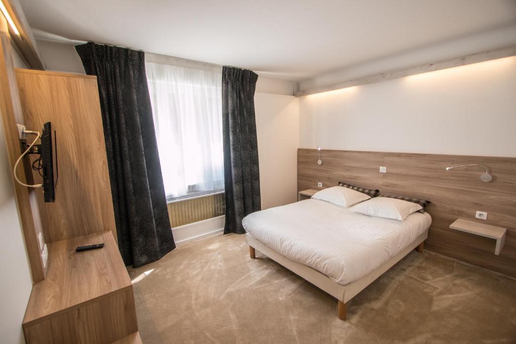 
a bedroom with a bed and a dresser at Hotel Les Voyageurs in Modane
