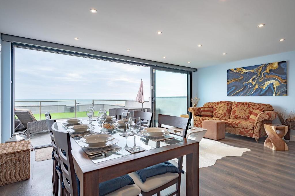 a living room with a table and a large window at Beach View Breeze Family Holiday Home on the Shore in Pevensey