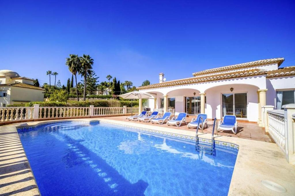 - une piscine avec des chaises et une maison dans l'établissement Villa La Gavina, à Jávea