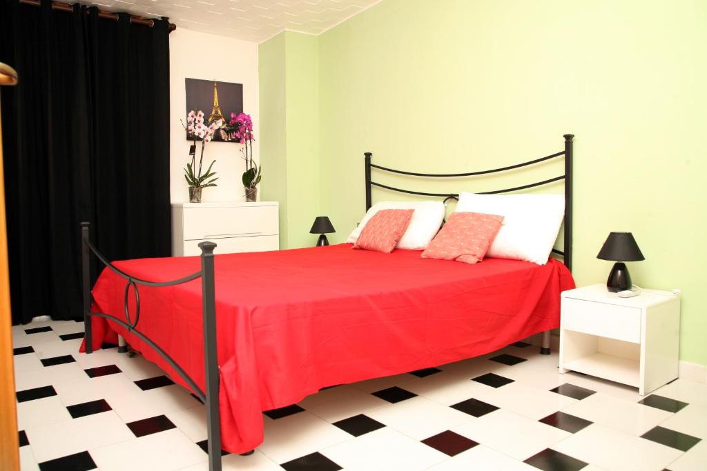 a bedroom with a red bed with a black and white floor at De Amicis Apartment in Cagliari