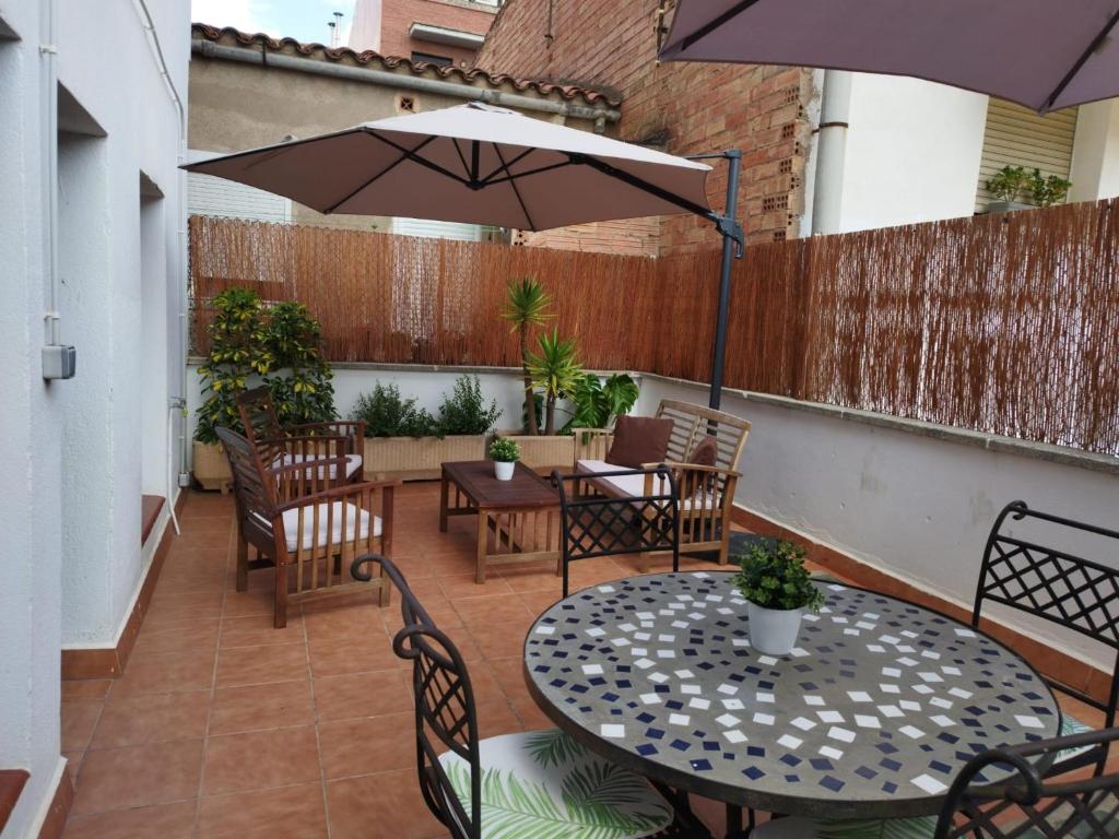 un patio con mesa, sillas y sombrilla en Apartaments IXA, en Manresa
