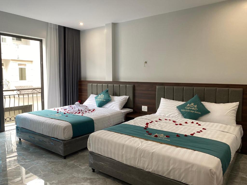 two beds in a hotel room with flowers on them at Tuần Châu HQT in Ha Long