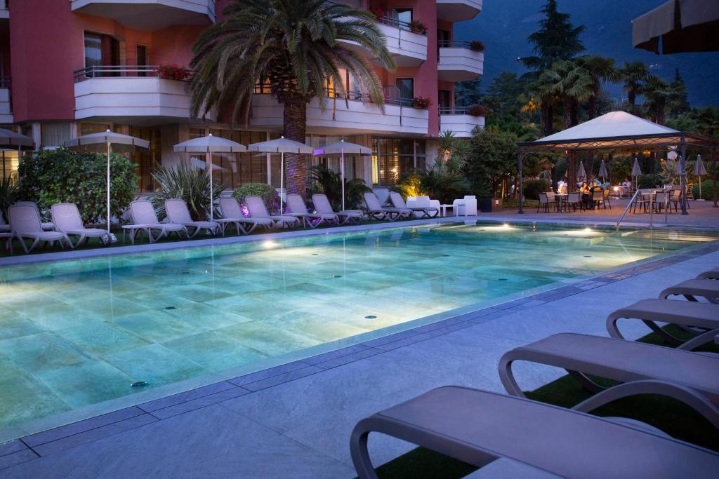 a swimming pool in front of a hotel at night at Palace Hotel Città in Arco