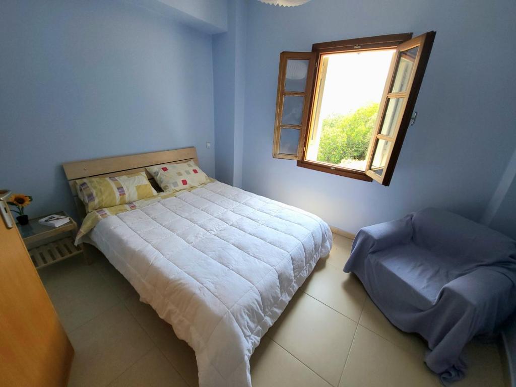 a blue bedroom with a bed and a window at Studio in Upper Symi in Symi