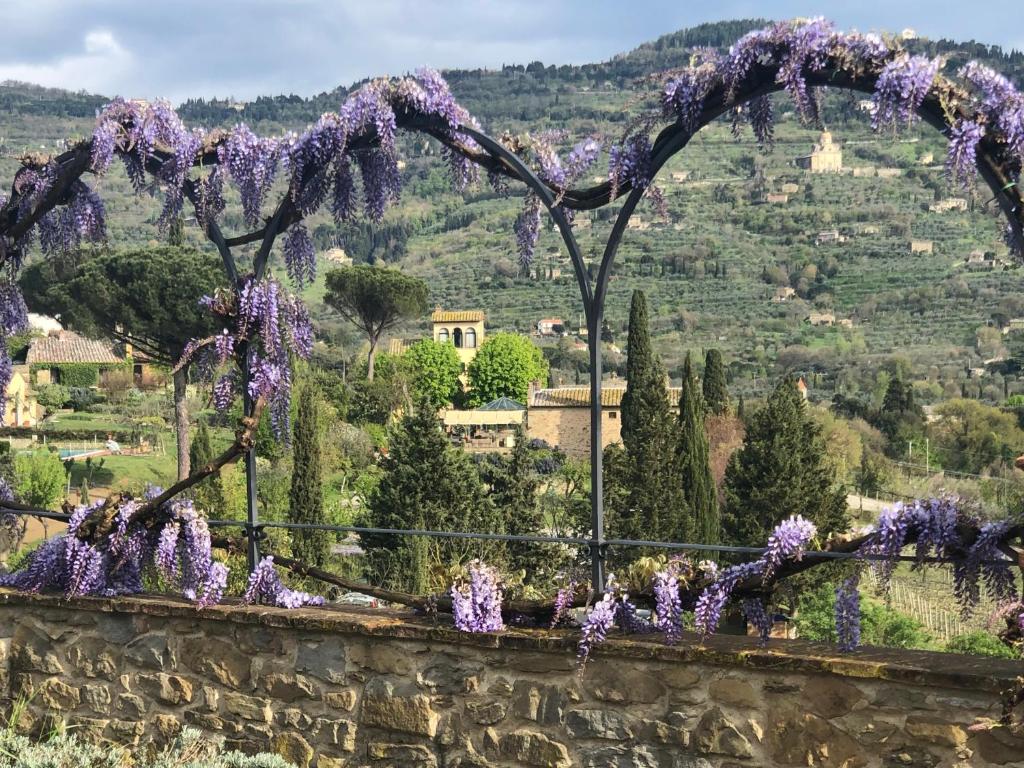 a garden with purple flowers on a stone wall at Relais & Châteaux Il Falconiere in Cortona