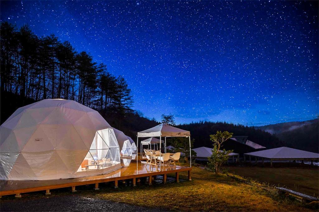 uma tenda com mesas e cadeiras sob um céu nocturno em 温泉グランピングWooods芸北 