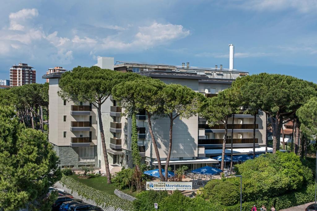 un edificio con árboles delante de él en Hotel Meridianus, en Lignano Sabbiadoro