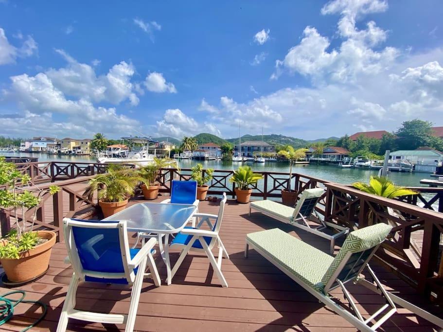 a deck with chairs and a table with a view of the water at Villa 218G Jolly Harbour in Jolly Harbour
