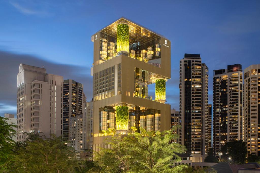 een hoog gebouw met lichten aan in een stad bij Pan Pacific Orchard in Singapore