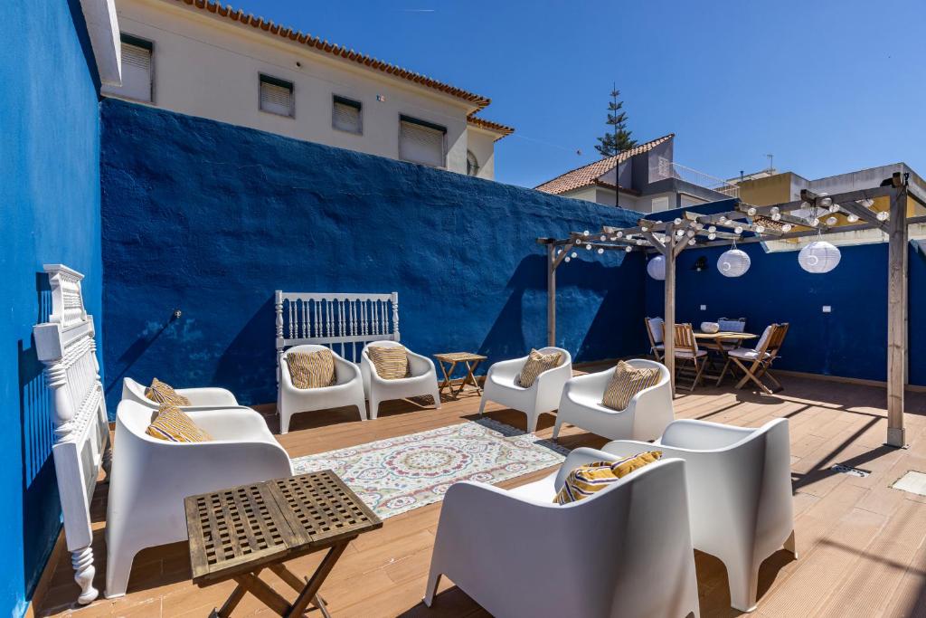 a patio with white chairs and a blue wall at Mom's House - Surf & Family by LovelyStay in Costa da Caparica