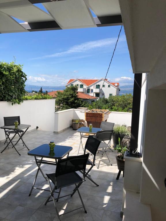 a patio with tables and chairs on a balcony at Karina Apartments in Supetar