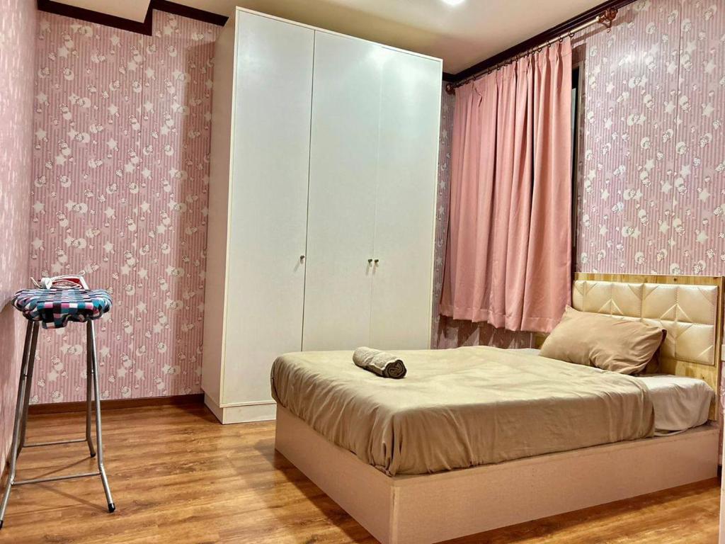 a bedroom with a bed and a dresser with pink walls at Jeff and Ricky Homestay 39 @ Vivacity (Huge Unit) in Kampong Tabuan