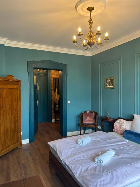 een slaapkamer met blauwe muren en een bed met witte lakens bij Apartament Baron ***** in Jelenia Góra