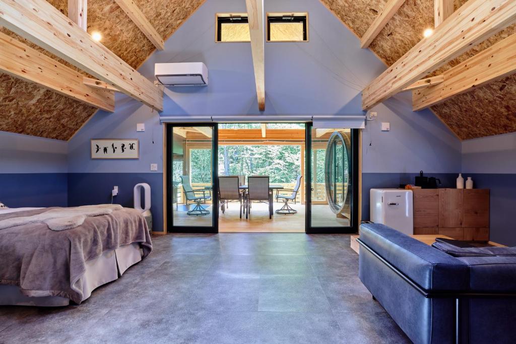 GRAN TOCORO. RESORT&GLAMPING في Narusawa: غرفة نوم بجدران زرقاء وسرير واريكة