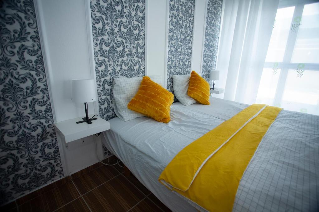 una camera da letto con letto, lenzuola e cuscini gialli di AG Apartment Gabčíkovo a Dunajská Streda