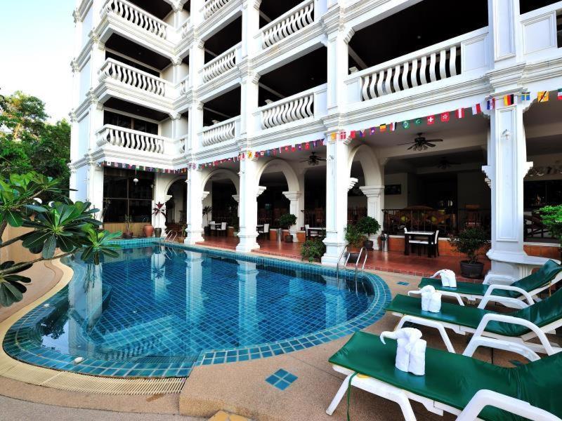 un hotel con piscina frente a un edificio en H.R.K.Resort en Patong Beach