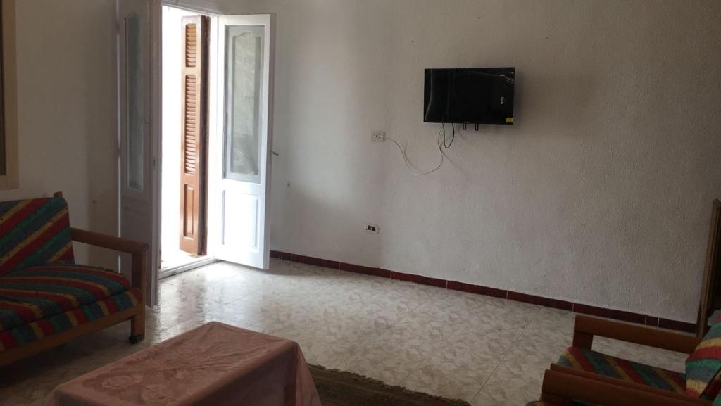 ein Wohnzimmer mit einem TV an der Wand in der Unterkunft قريه رمسيس الساحل الشمالي الكيلو ٤٥ in Dawwār Abū Maḩrūs