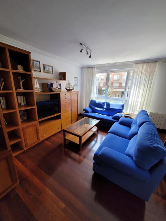 een woonkamer met twee blauwe banken en een tafel bij Nuevo! 3 habitaciones con garaje privado in Santander