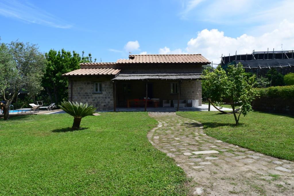 a small stone house with a grass yard at Villa Pontecorvo with Swimming Pool in Sant'Agnello