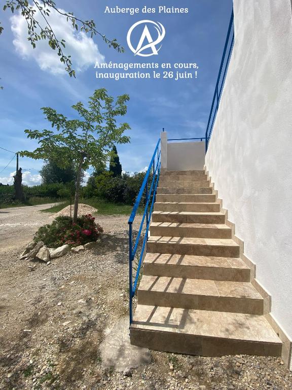 a staircase with a blue railing next to a building at Auberge des Plaines - Appartements avec terrasse in Arles