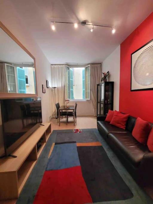 - un salon avec un canapé noir et un mur rouge dans l'établissement Vieux Nice Vibrant Central Apt, à Nice