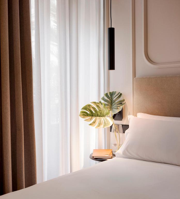 a bedroom with a bed and a window with a plant at Oliveira Rooms in Valencia