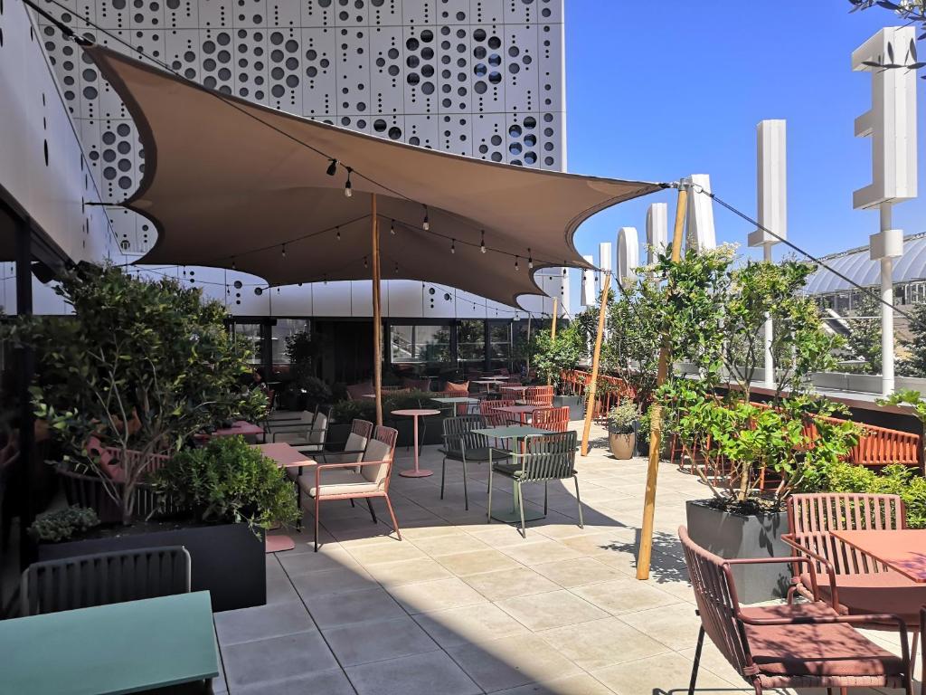 eine Terrasse mit Tischen, Stühlen und Pflanzen in der Unterkunft Belaroïa Montpellier Centre Saint Roch in Montpellier