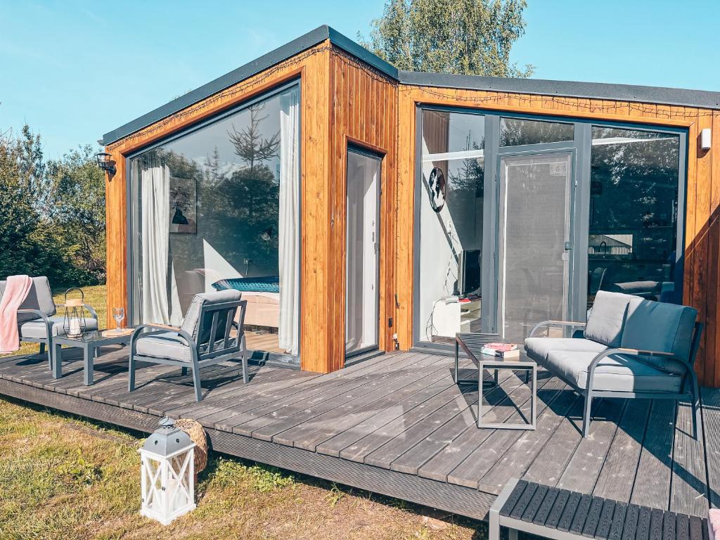 une petite maison avec une terrasse et deux chaises dans l'établissement Domek Golf i Jezioro, à Tomaszkowo