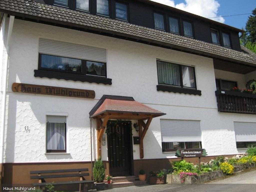 a white building with a wooden door and a bench at Haus Mühlgrund in Bad Wildbad