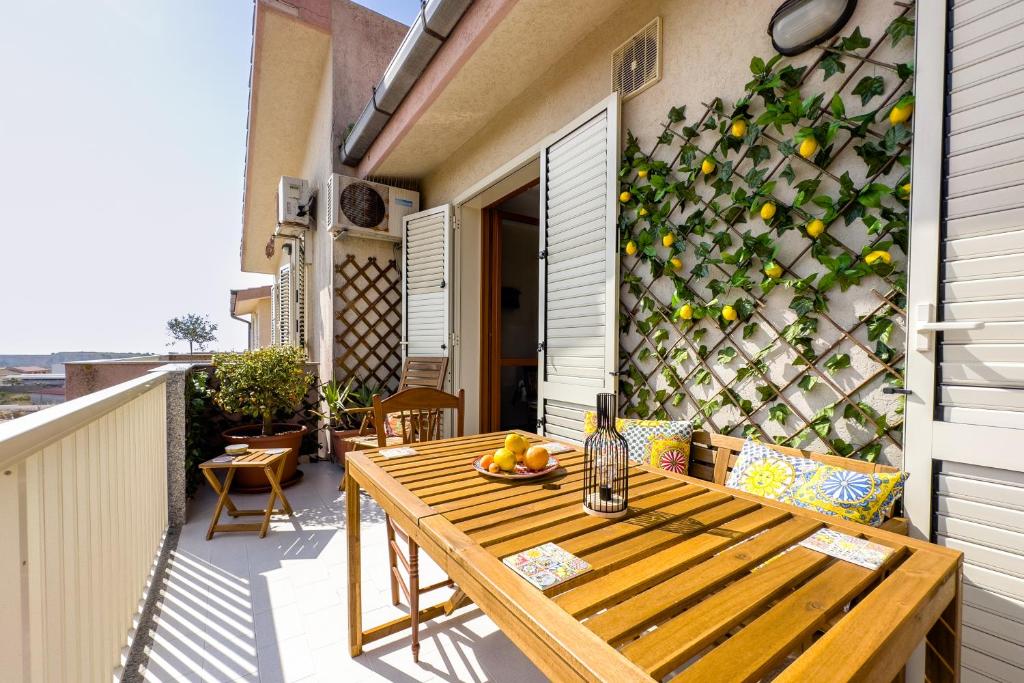 a wooden table on a balcony with a wall of lemons at Casa Vacanza Germano - Vivi un soggiorno da sogno - 160m2 di comfort e vista mare in Sicilia! in Pachino