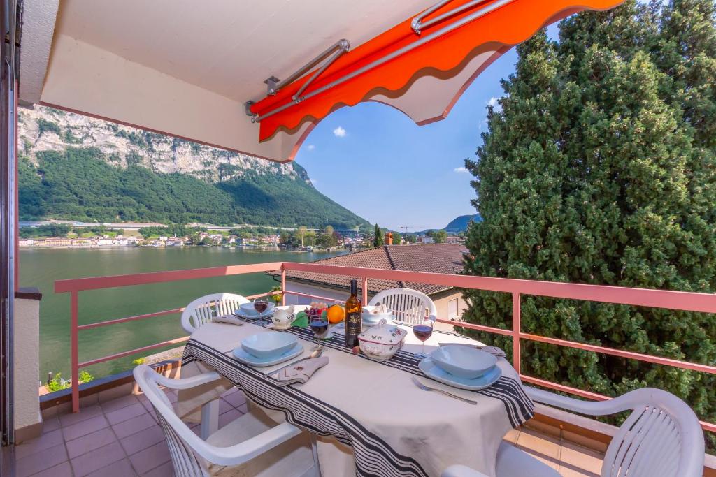 a table and chairs on a balcony with a view of the water at Casa Bader in Riva San Vitale