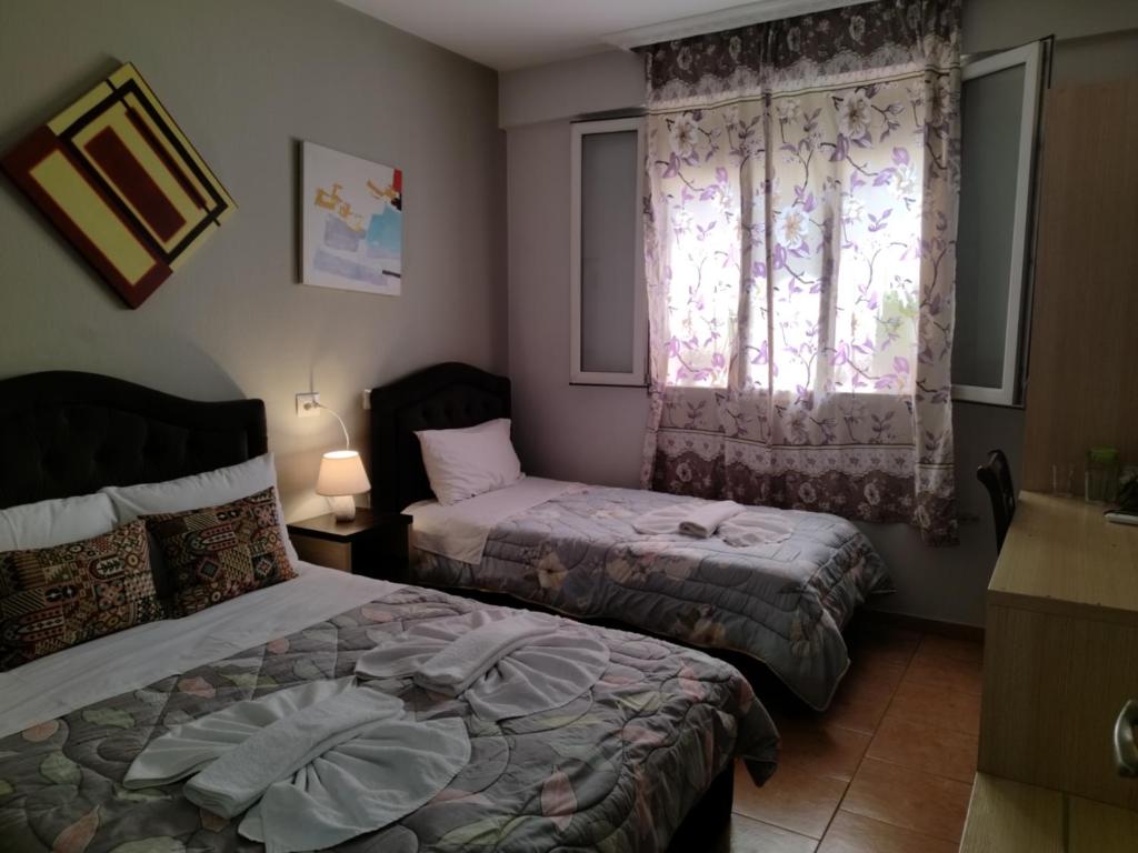 1 dormitorio con 2 camas y ventana en Guest House De Rada en Tirana