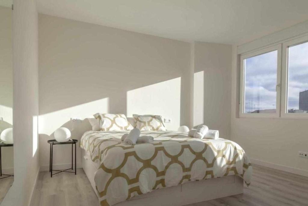 una camera bianca con un grande letto e una finestra di Apartamento Roncudo 4º planta a La Coruña