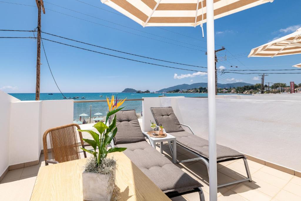 een patio met stoelen, een tafel en een parasol bij Mouria Studios & Apartments in Laganas
