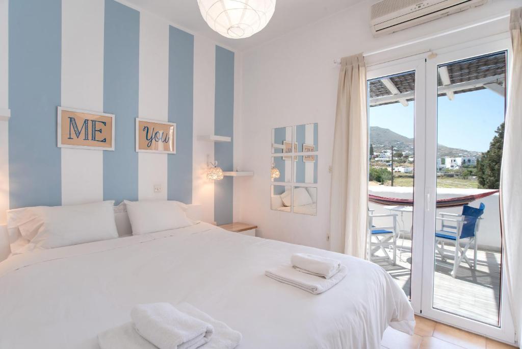 a white bedroom with a bed and a balcony at Livadia Seaside Studios 14 in Parikia