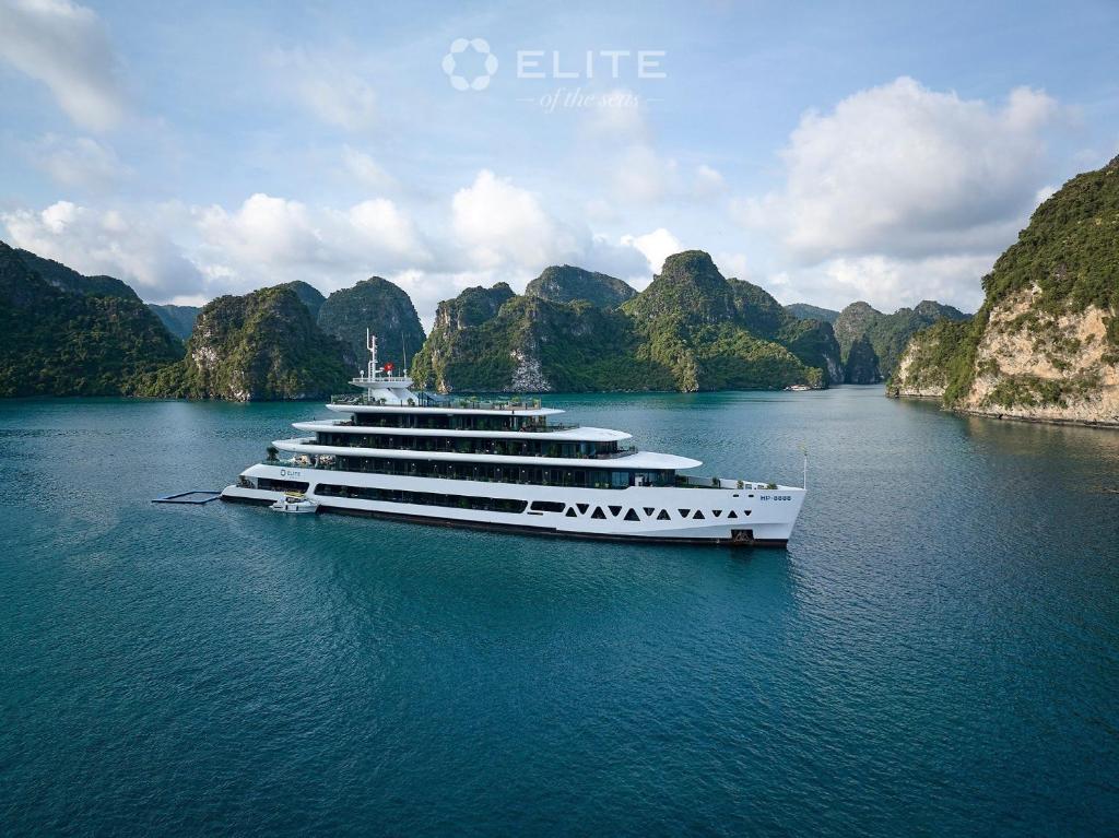 un grupo de barcos en el agua con montañas en el fondo en Elite of the Seas en Ha Long