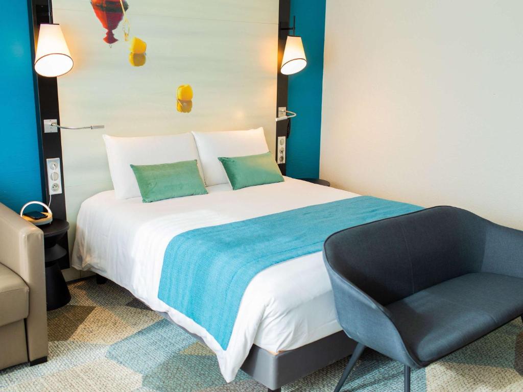 een slaapkamer met een groot bed en een stoel bij Mercure Lorient Centre in Lorient