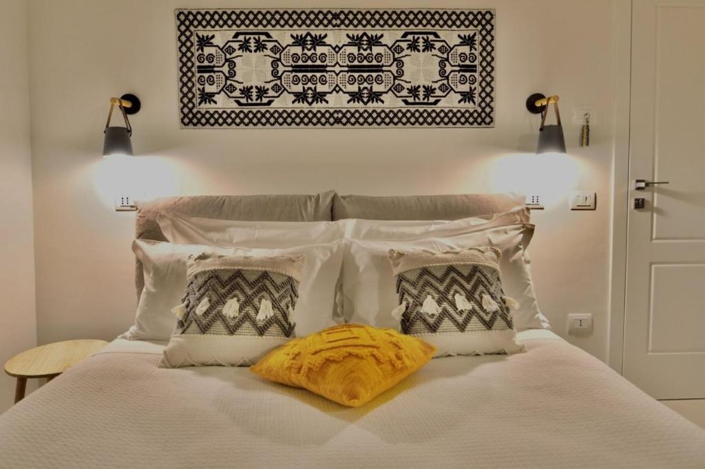 Una cama con almohadas blancas y una manta amarilla. en Almarì, en Cagliari