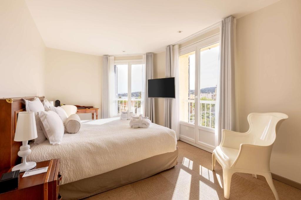 a white bedroom with a large bed and a chair at Best Western Hotel Matisse in Sainte-Maxime