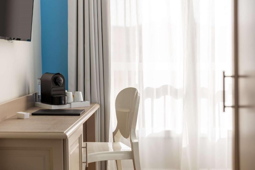 a room with a desk with a chair and a microwave at Best Western Hotel Matisse in Sainte-Maxime