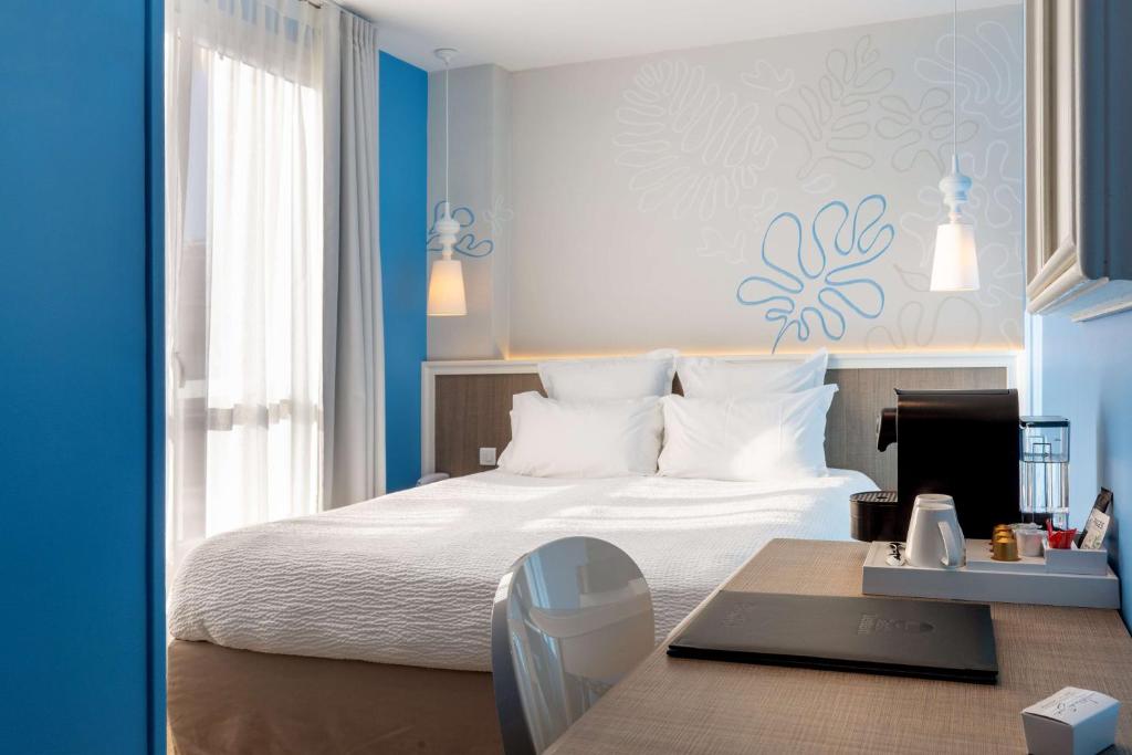 a bedroom with a bed and a desk with a laptop at Best Western Hotel Matisse in Sainte-Maxime